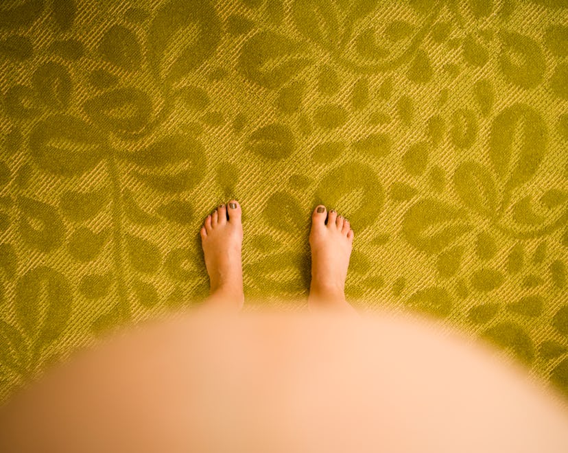 birds eye view of feet with pregnant belly bump in the foreground