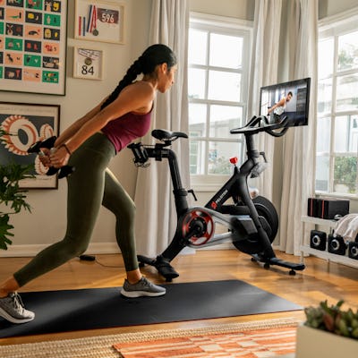 A woman is seen working out next to a Peloton bike in her apartment.