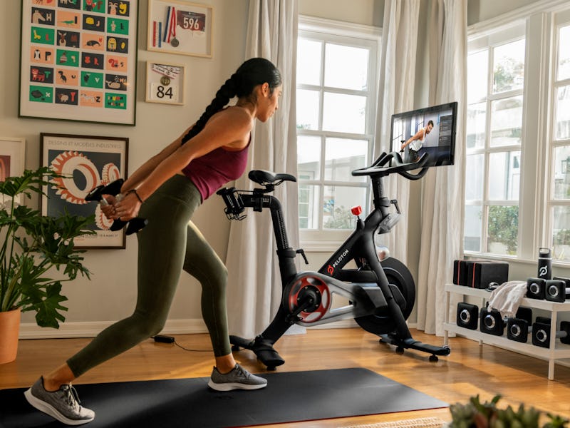 A woman is seen working out next to a Peloton bike in her apartment.