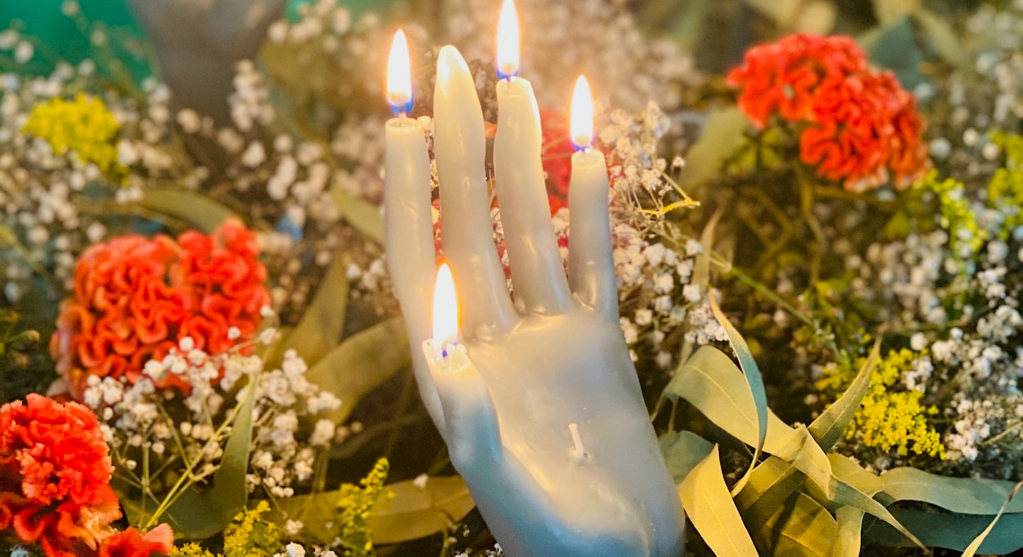 lit hand candle with a background of flowers