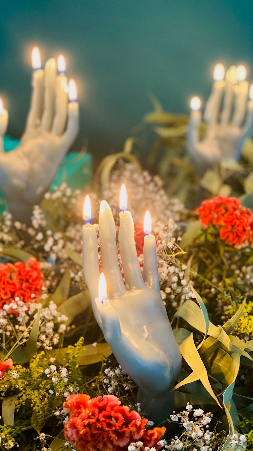 lit hand candle with a background of flowers