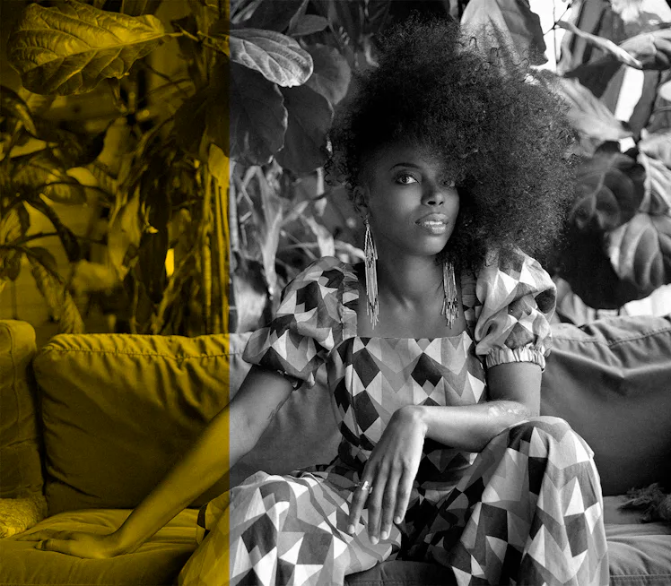 Sasheer Zamata sitting on a couch and posing for a photo