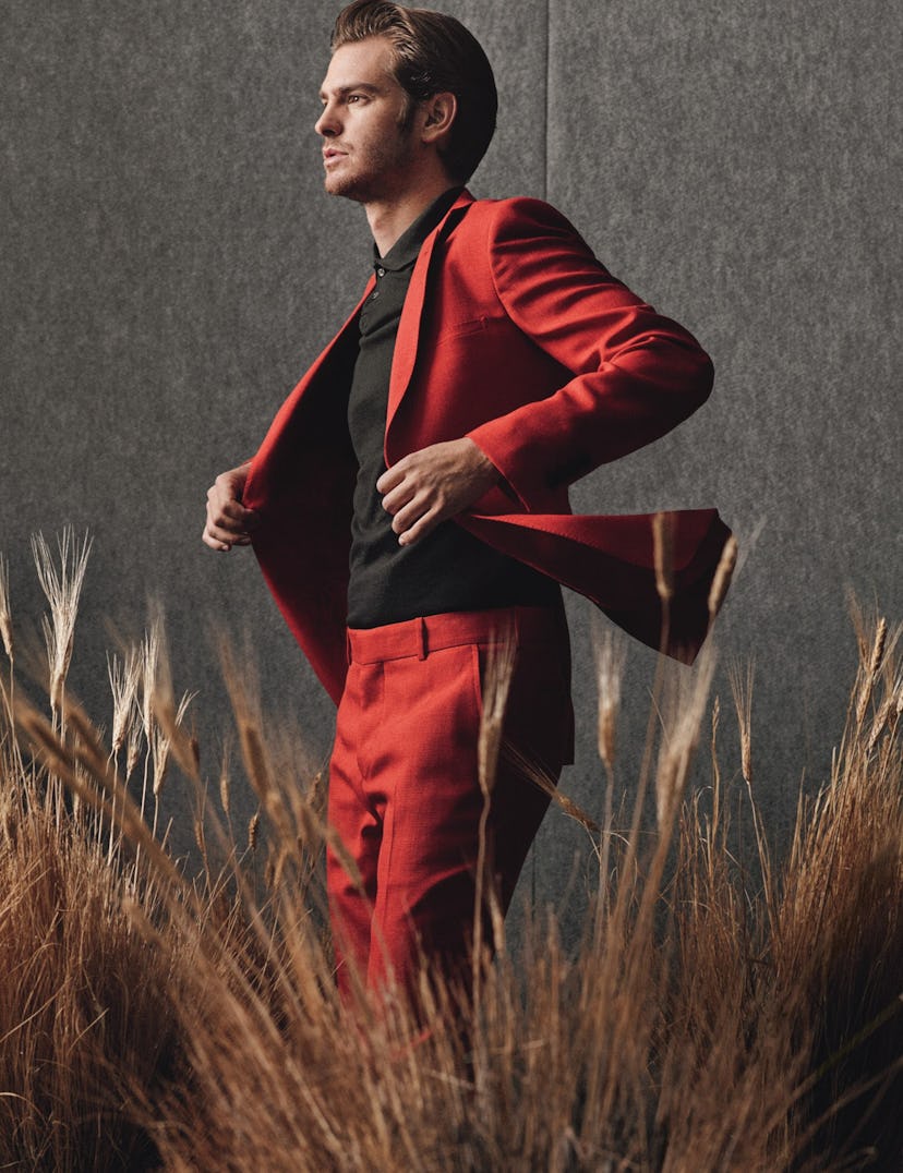 Andrew Garfield in a red suit looking at something in the distance.