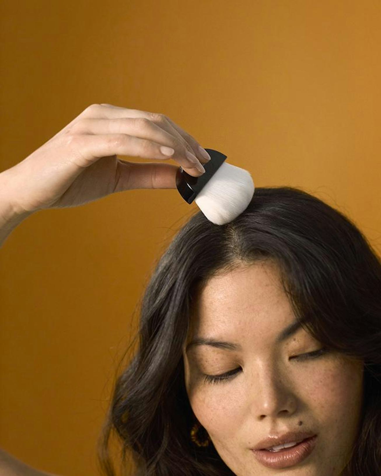 Person runs brush from Crown Affair Dry Shampoo through hair