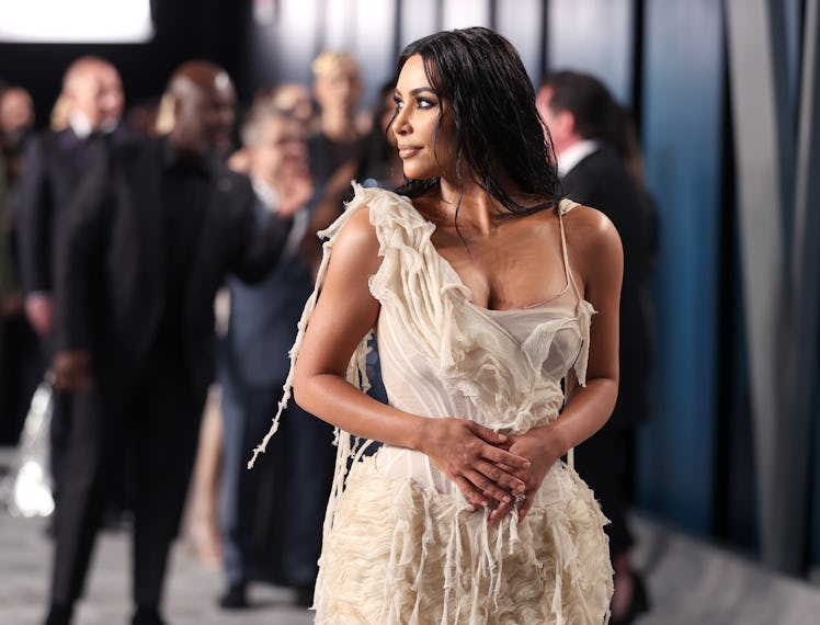 Kim Kardashian on a red carpet in artfully tattered dress. 