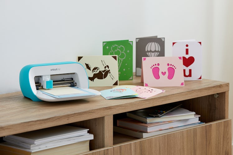 The Cricut Joy sits on a desk next to DIY cards made from it.