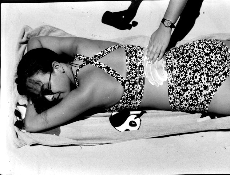 A person putting sunscreen on a body of a woman
