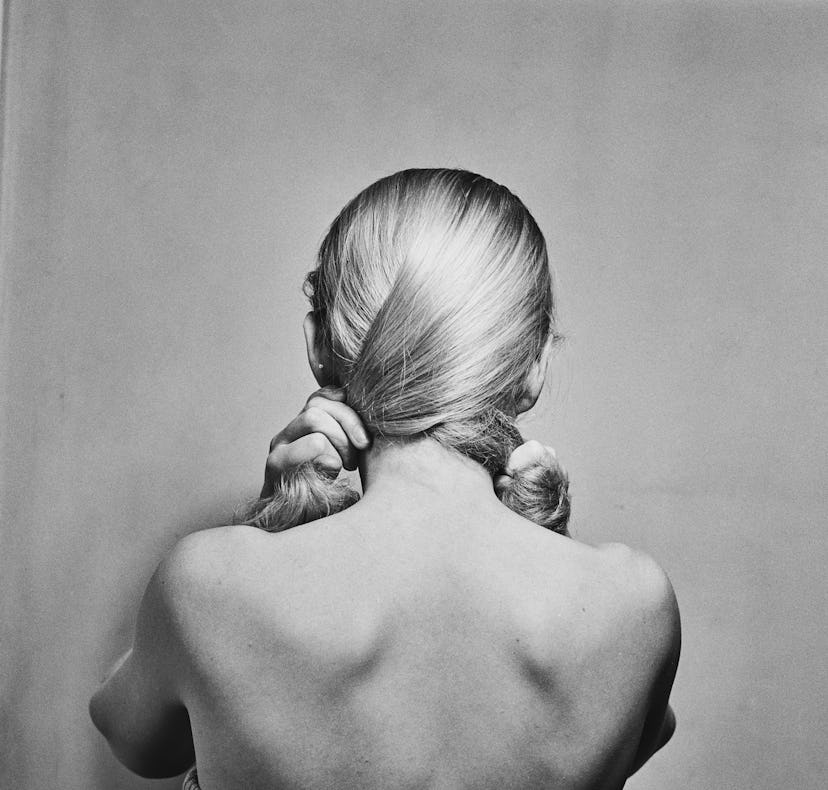 Model posing with her head turned to wall, showing her naked back and hair.