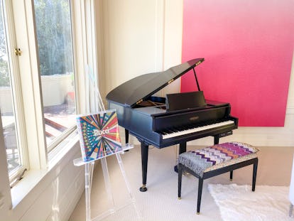 Rachel Zoe interior design home decor with a black grand piano, a piano chair with a vintage throw a...