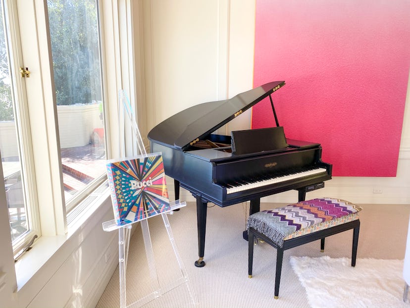 Rachel Zoe interior design home decor with a black grand piano, a piano chair with a vintage throw a...