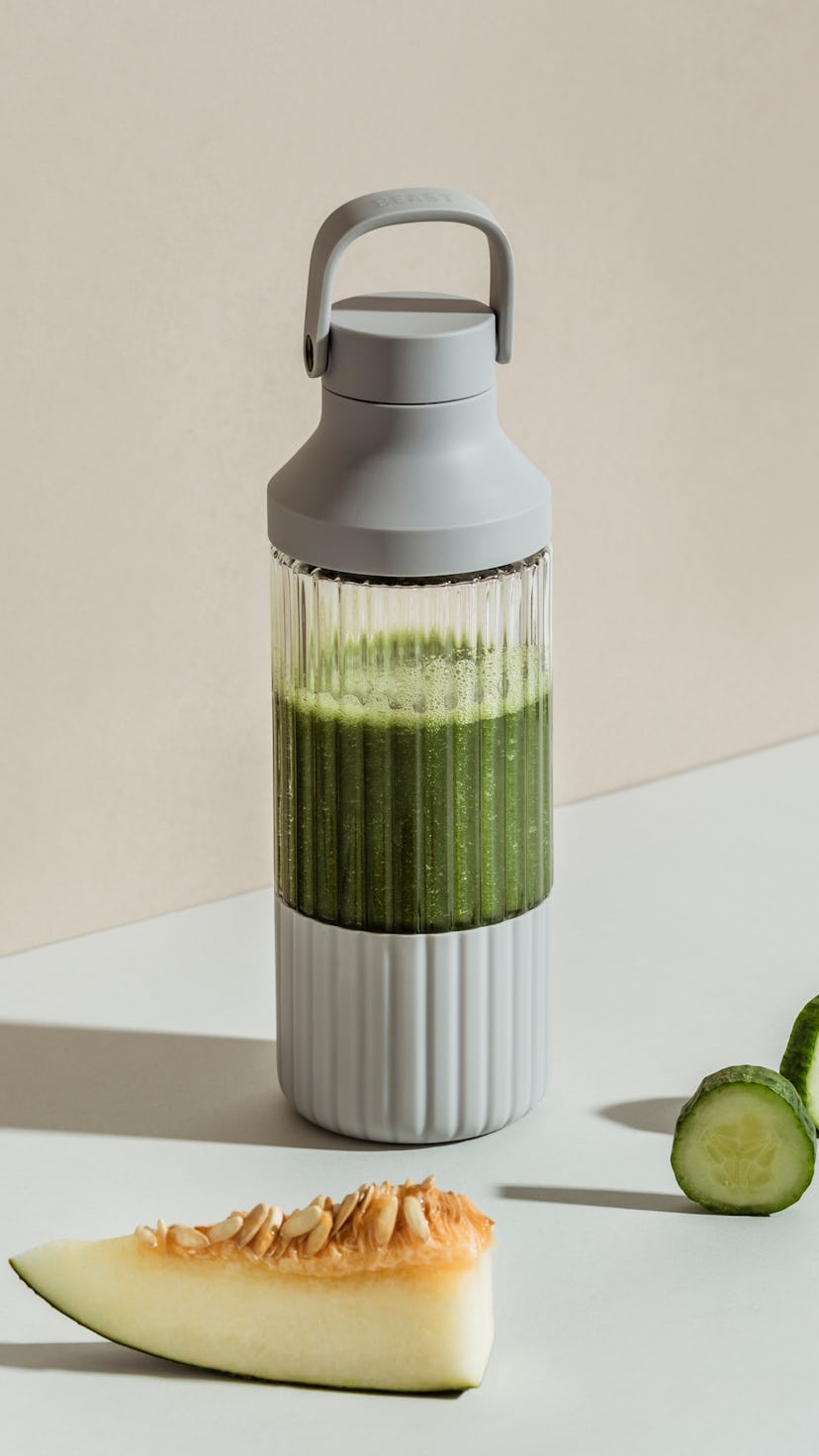 A green smoothie can be seen inside a sleek design B10 blender.