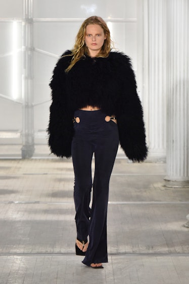 A model walking the Dion Lee runway at New York Fashion Week in a black fur coat and high-waisted pa...