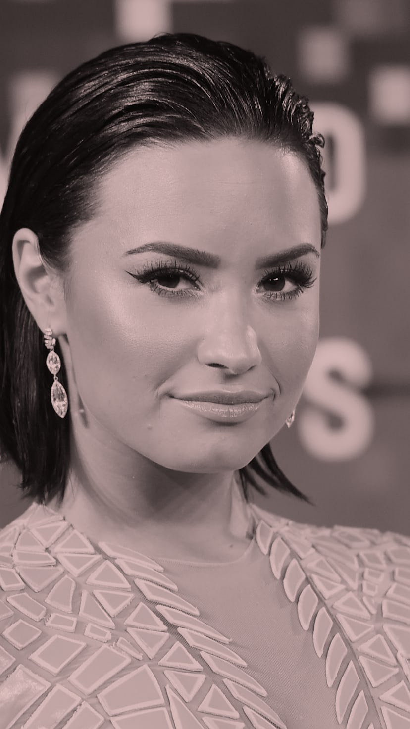 Demi Lovato, with short brown hair tucked behind ears, is wearing a pink dress