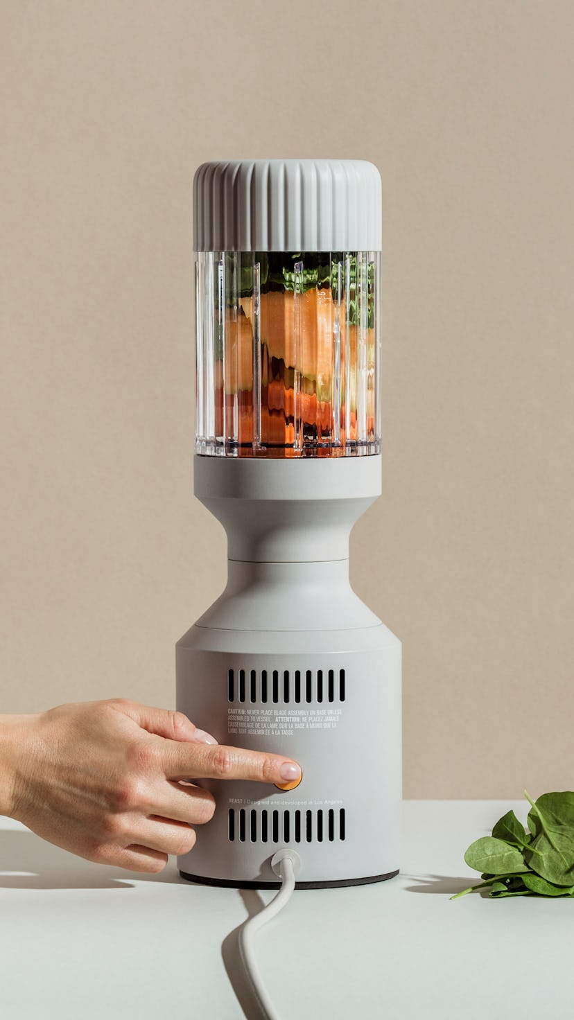 A B10 blender is seen with papaya, greens, and other fruits inside the blending glass.