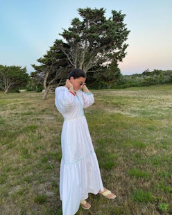 A woman posing in a long white linen affordable dress for Summer