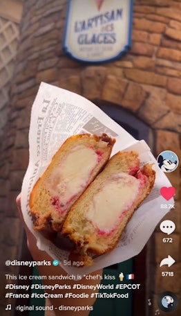 A woman holds up a brioche bun ice cream sandwich at Disney World. 