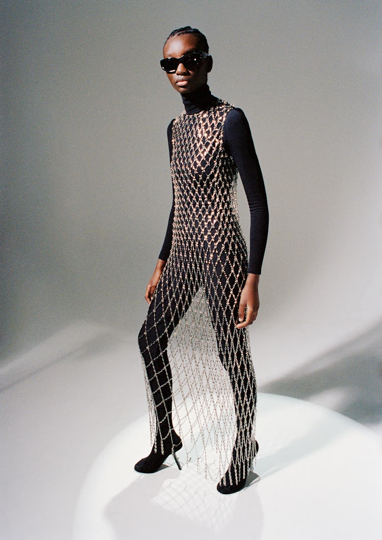 Assa Baradji wears a Balenciaga chain dress, sunglasses, and pantalegging shoes; Wolford turtleneck ...