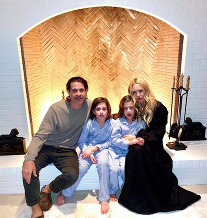 Rachel Zoe with her husband and two daughters at a white fireplace 