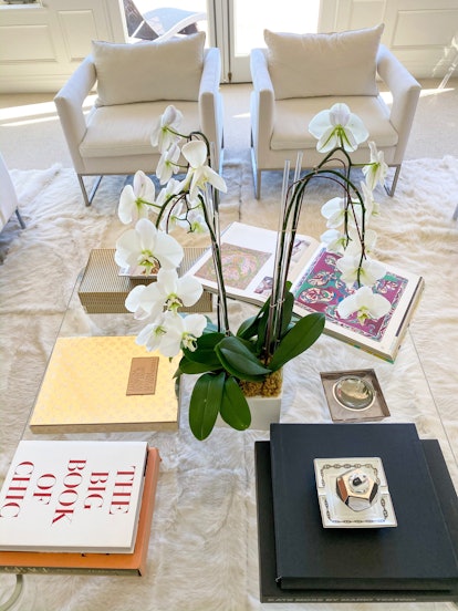 Rachel Zoe interior design home decor with a coffee table featuring various books and orchids in the...