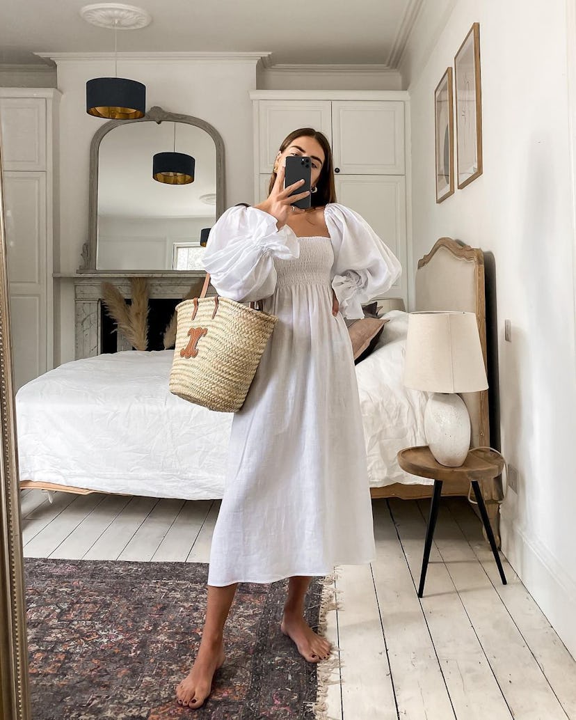 A woman taking a mirror selfie in a long white puff-sleeved affordable dress for Summer
