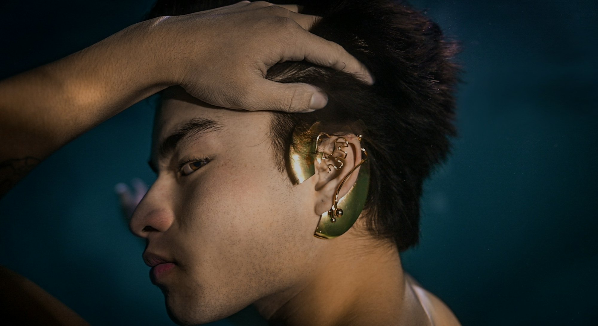 A model is seen showcasing ear jewel hearing implants underwater. Jewelry. Earrings. Fashion. Design...