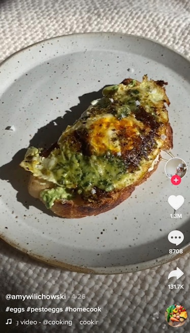 Pesto egg avocado toast sits on the table with salt sprinkled on top. 