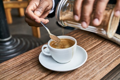 A person putting sugar in coffee