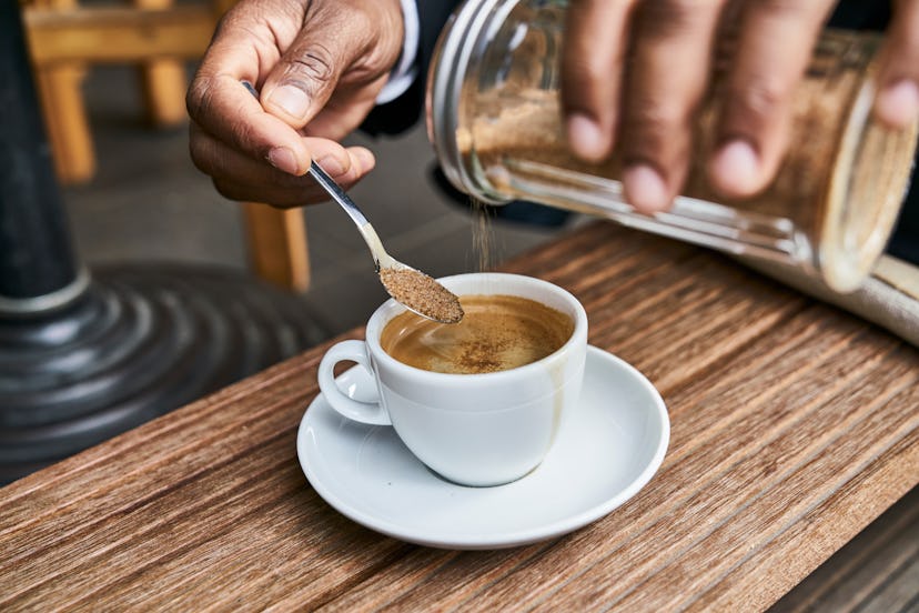 A person putting sugar in coffee