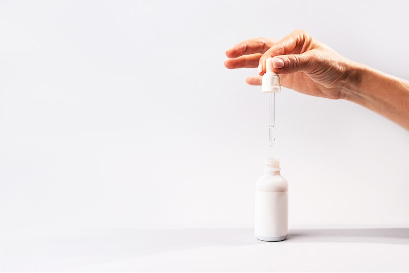 A woman opening a bottle and holding a dropper from an over-the-counter retinoids serum