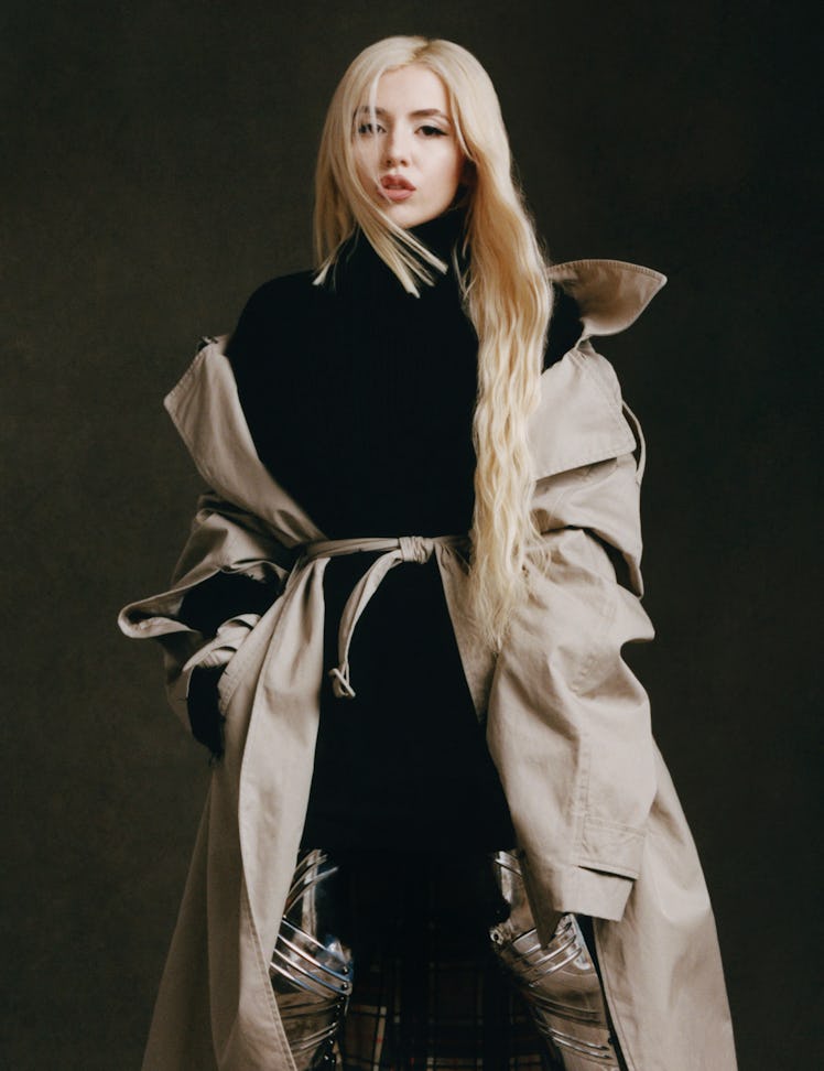 Ava Max wears a Balenciaga trenchcoat, turtleneck, leggings, and boots.