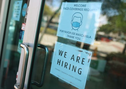 The door of a store with a mask sign and a 'We are hiring' sign as employees aren't rushing back to ...