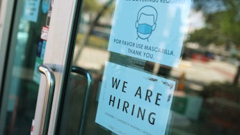 The door of a store with a mask sign and a 'We are hiring' sign as employees aren't rushing back to ...