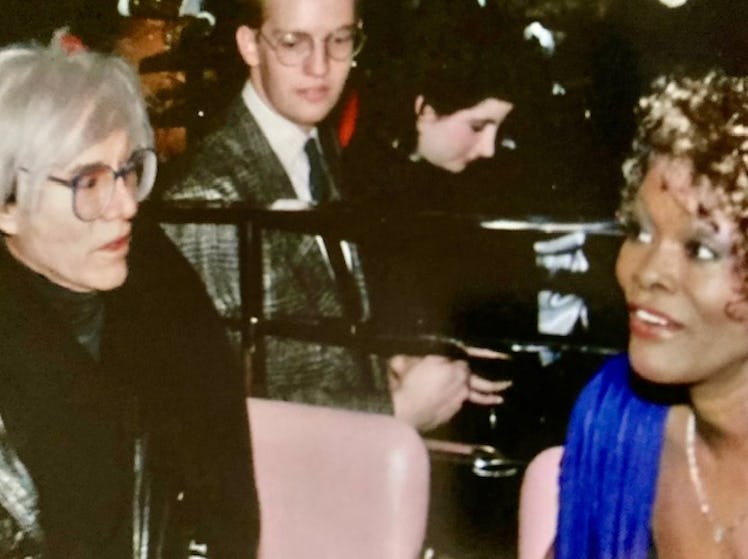 Dionne Warwick and Andy Warhol sitting at a table talking, at the launch party for her perfume