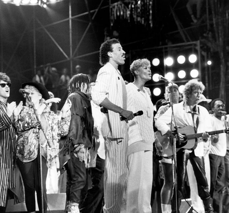 Dionne Warwick performing at Live Aid in 1985 on stage with Lionel Richie and a band behind them 