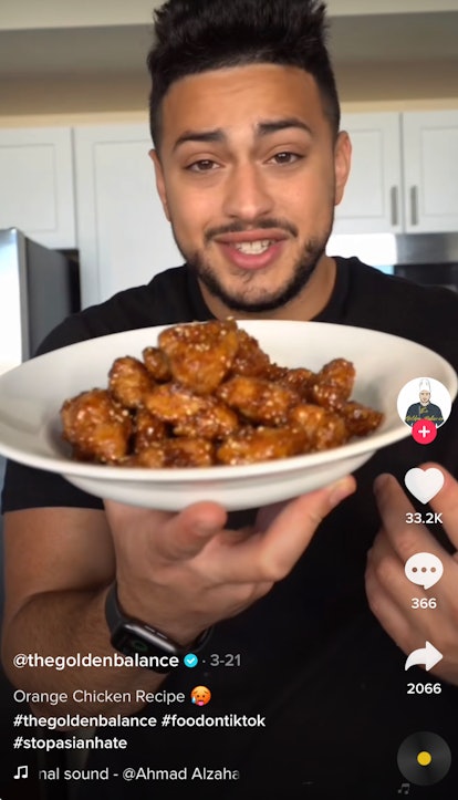 A man holds up a bowl of orange chicken from TikTok in his kitchen. 