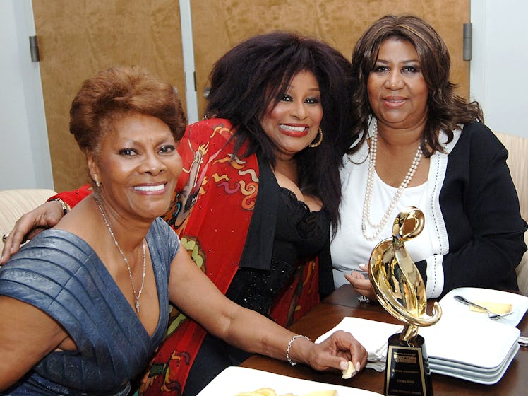 Dionne Warwick, Chaka Khan and Aretha Franklin sitting together and smiling with an award on the tab...