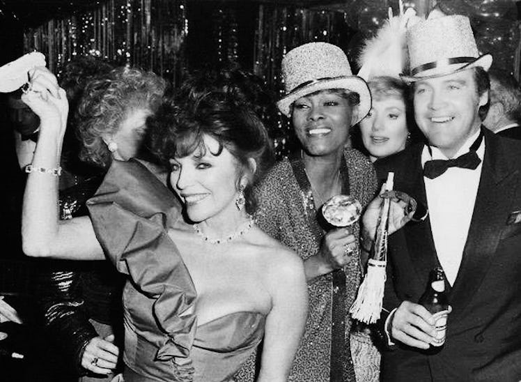 Dionne Warwick with Joan Collins and Lee Majors at Aaron Spelling’s New Year's Eve party, wearing ha...