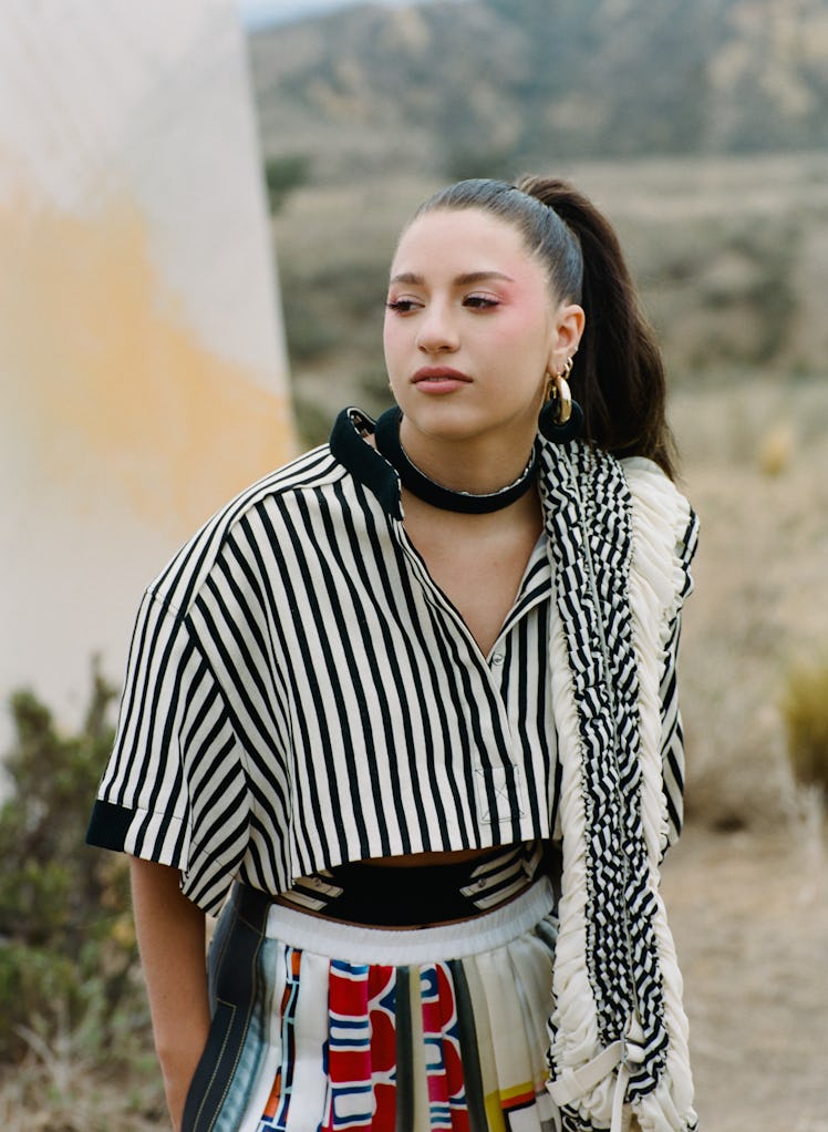 Former 'Dance Moms' star Kenzie Ziegler wears a black and white striped Louis Vuitton shirt while po...