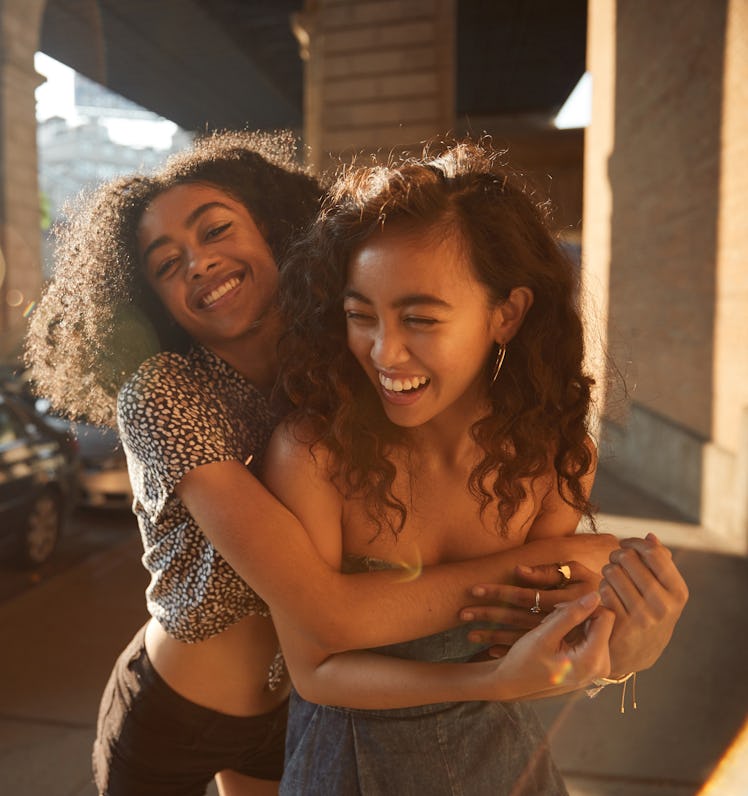 Young female best friends with compatible astrological qualities smiling and hugging