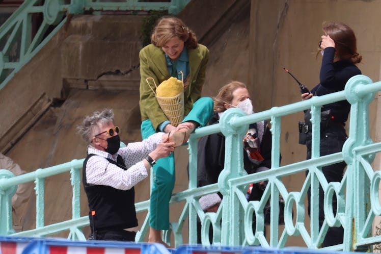 Emma Corrin climbing over a railing