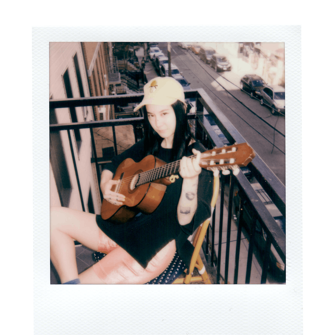 Michelle Zauner posing with a guitar on the balcony.