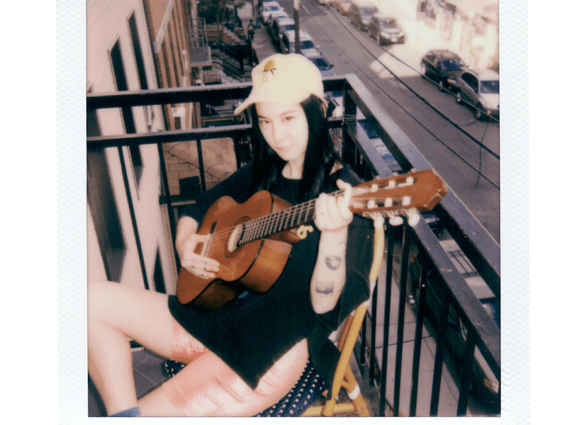 Michelle Zauner posing with a guitar on the balcony.