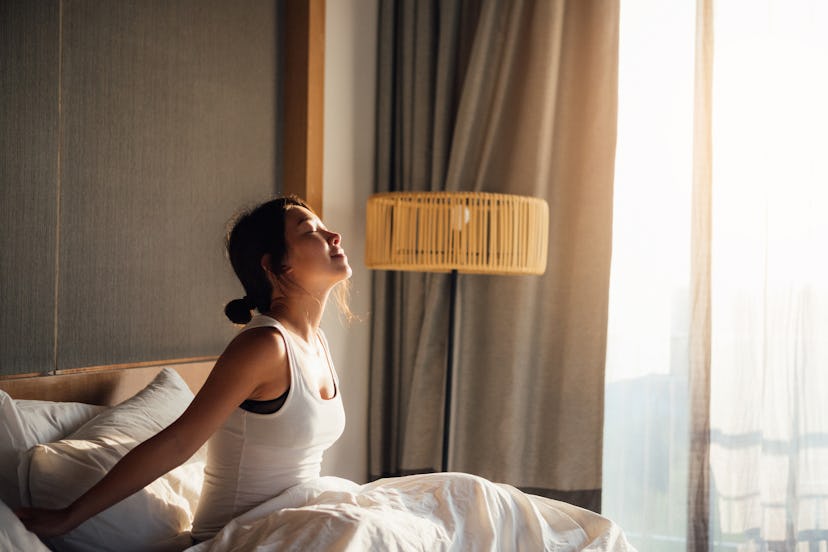 A woman stretching her arms and back after waking up after she got enough sleep