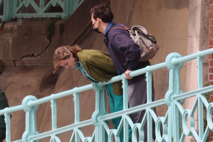 Emma Corrin and Harry Styles leaning over a railing