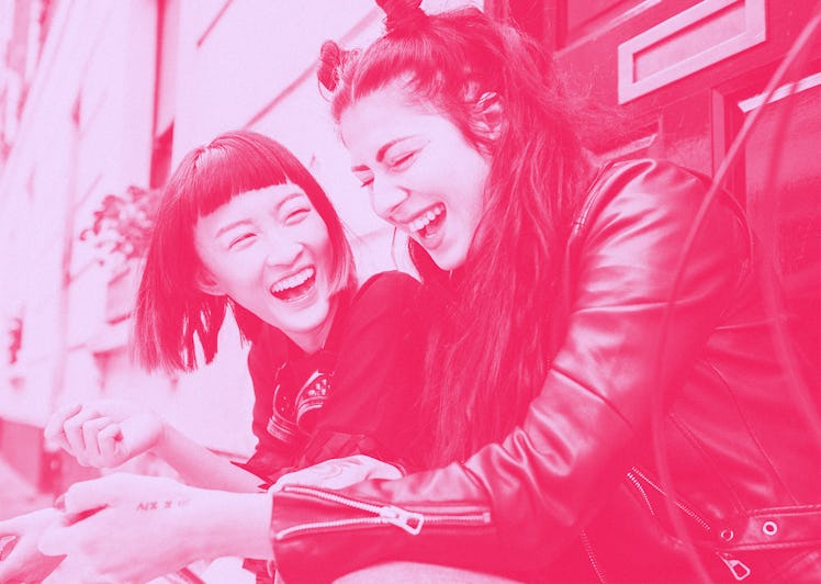 Two female BFFs sitting on a doorstep and laughing