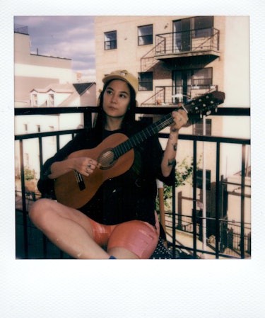 Michelle Zauner on the balcony playing a guitar.