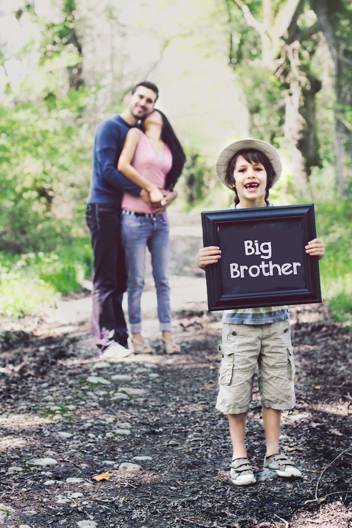 boy holding "big brother" sign with pregnant mom and dad in the background