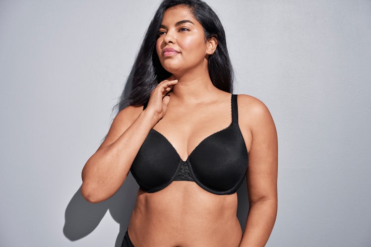 A woman with olive skin and dark brown hair wearing a black bra while modeling for Wacoal's mybraFit...