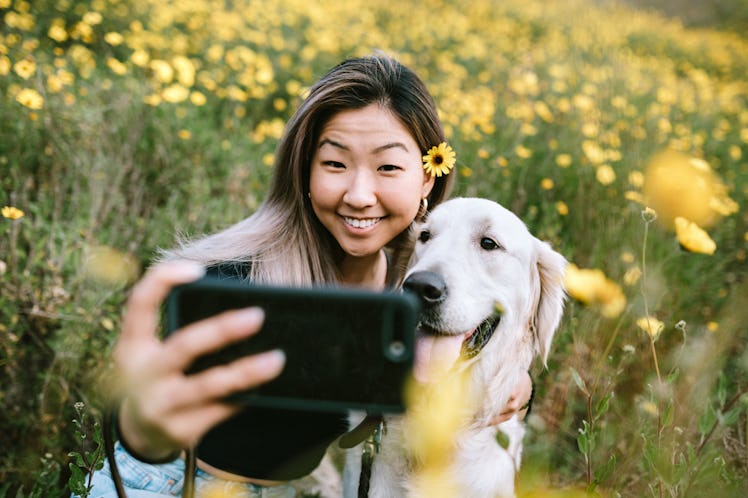 Woman posing for selfie with dog.