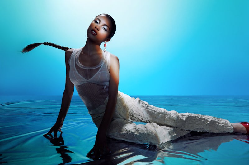 Olivia Rodrigo in a white see through combination on a watery surface.